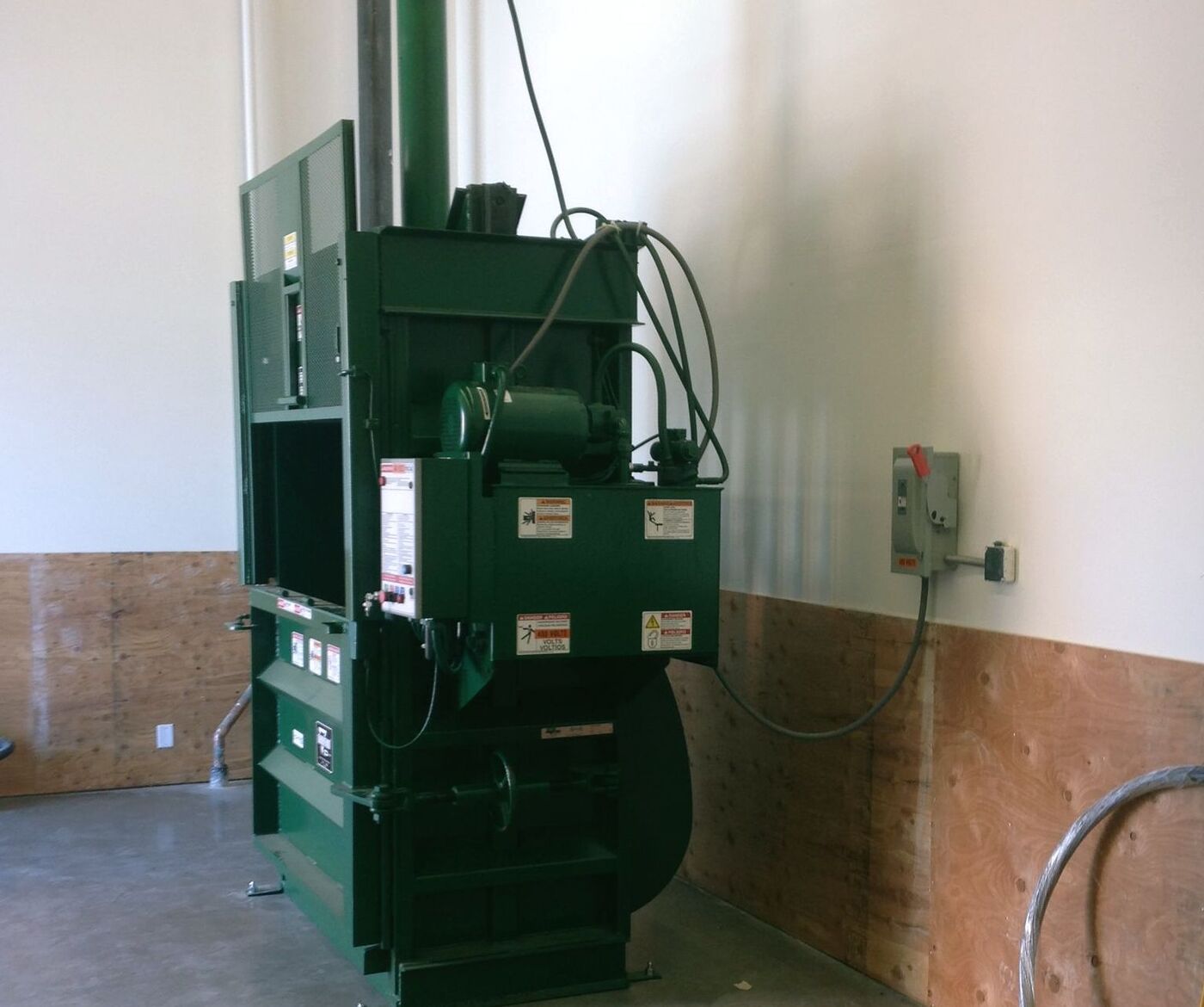 Green vertical baler installed indoors